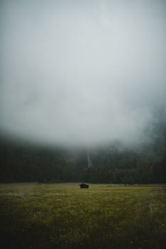 薄雾笼罩着绿色的草甸、茂密的林地以及一座废弃的旧木屋