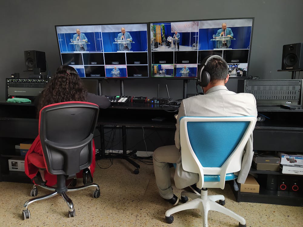 Free Back view of broadcast editors working at panel with equipment and big monitors Stock Photo