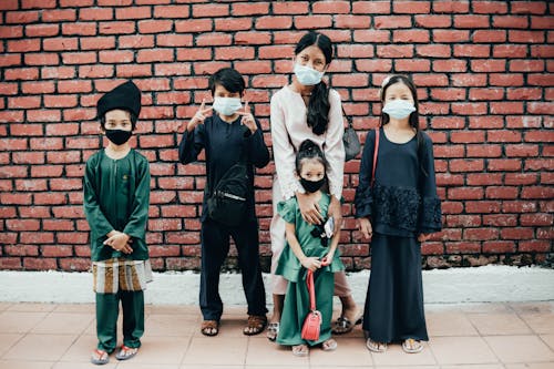 Group of Kids Wearing Face Masks Standing near the Brick Wall
