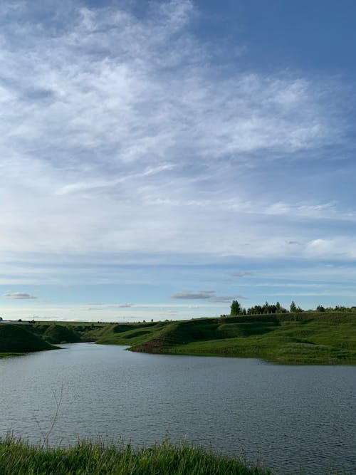 Rippling water surface of river flowing along green grassy shore in nature in daylight