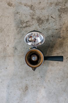 Overhead shot of a vintage moka pot with open lid on a textured stone background, showcasing rustic charm.
