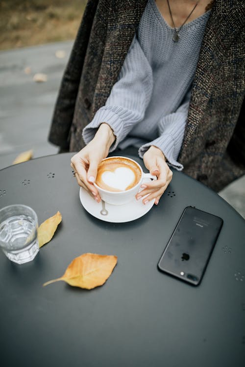 Free A Person Holding a Cup of Coffee on Black Table Stock Photo