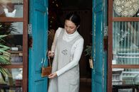 Positive Asian female in casual clothes hanging open sign on shabby blue door of rural weathered shop