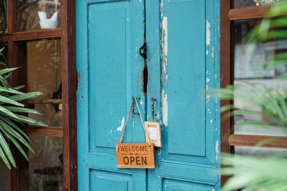 Best Smart Locks for Front Door Security in 2026: Beginner’s Complete Guide A rustic blue door with a wooden welcome sign showcasing an open establishment.