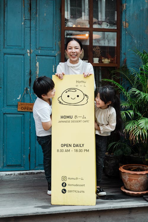 Photo of Family Smiling While Standing Near Signage