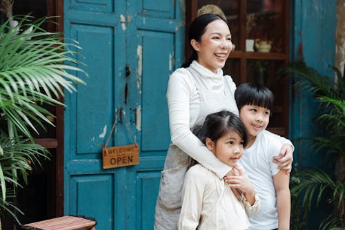 Free Photo of Woman Smiling While Hugging Her Children Stock Photo