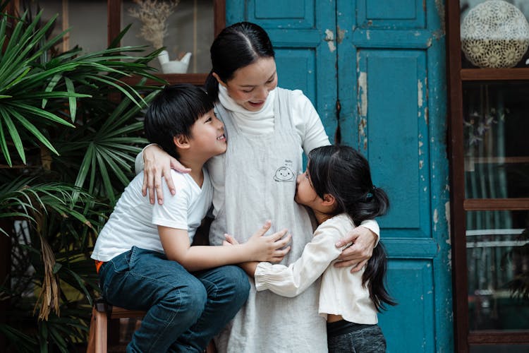 Cheerful Mother With Kids Near Shabby Blue Wall