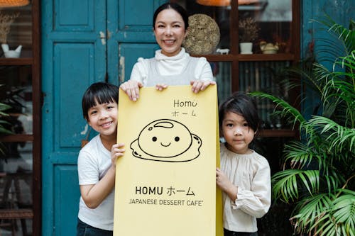 Photo of Family Smiling While Holding Signage