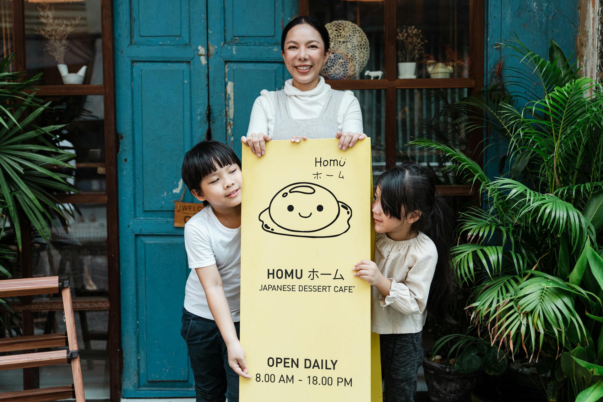 Happy family outside a Japanese dessert café holding a welcoming sign.