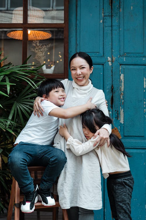 Free Photo of Woman Hugging Her Children While Smiling Stock Photo