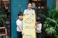 Photo of Family Smiling While Standing Near Signage