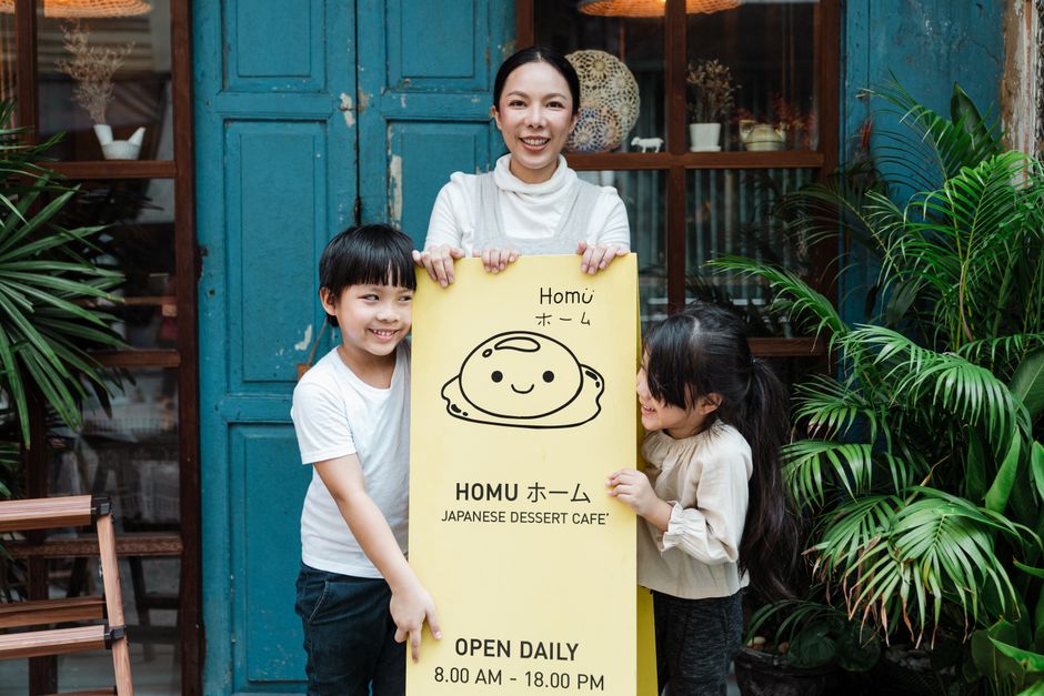 日本のデザートカフェで看板を持っている幸せな家族、共に楽しい時間を過ごしています。