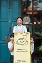 Photo of Family Smiling While Standing Near Signage