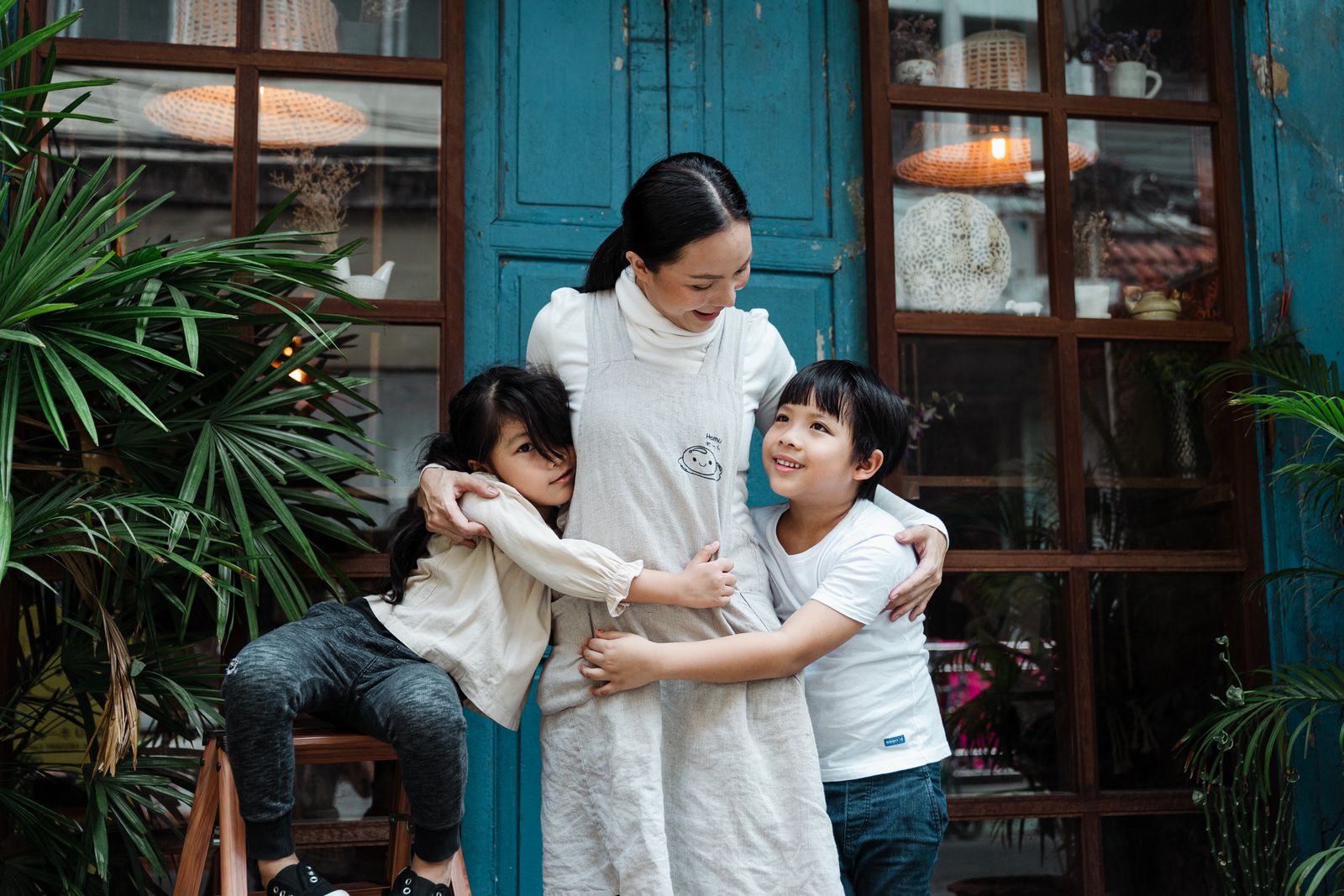 A smiling Arizona mother laughing and hugging her two young children at home