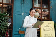 Cheerful woman with clipboard near cafe entrance