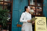 一名女子拿着平板电脑，站在一家日本甜点咖啡馆外