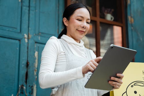 Free Woman in White Long Sleeve Shirt Holding Silver Tablet Computer Stock Photo