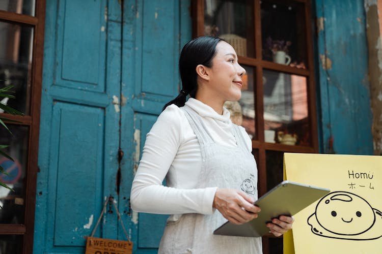 Photo Of Woman Standing While Holding Silver Tablet Computer