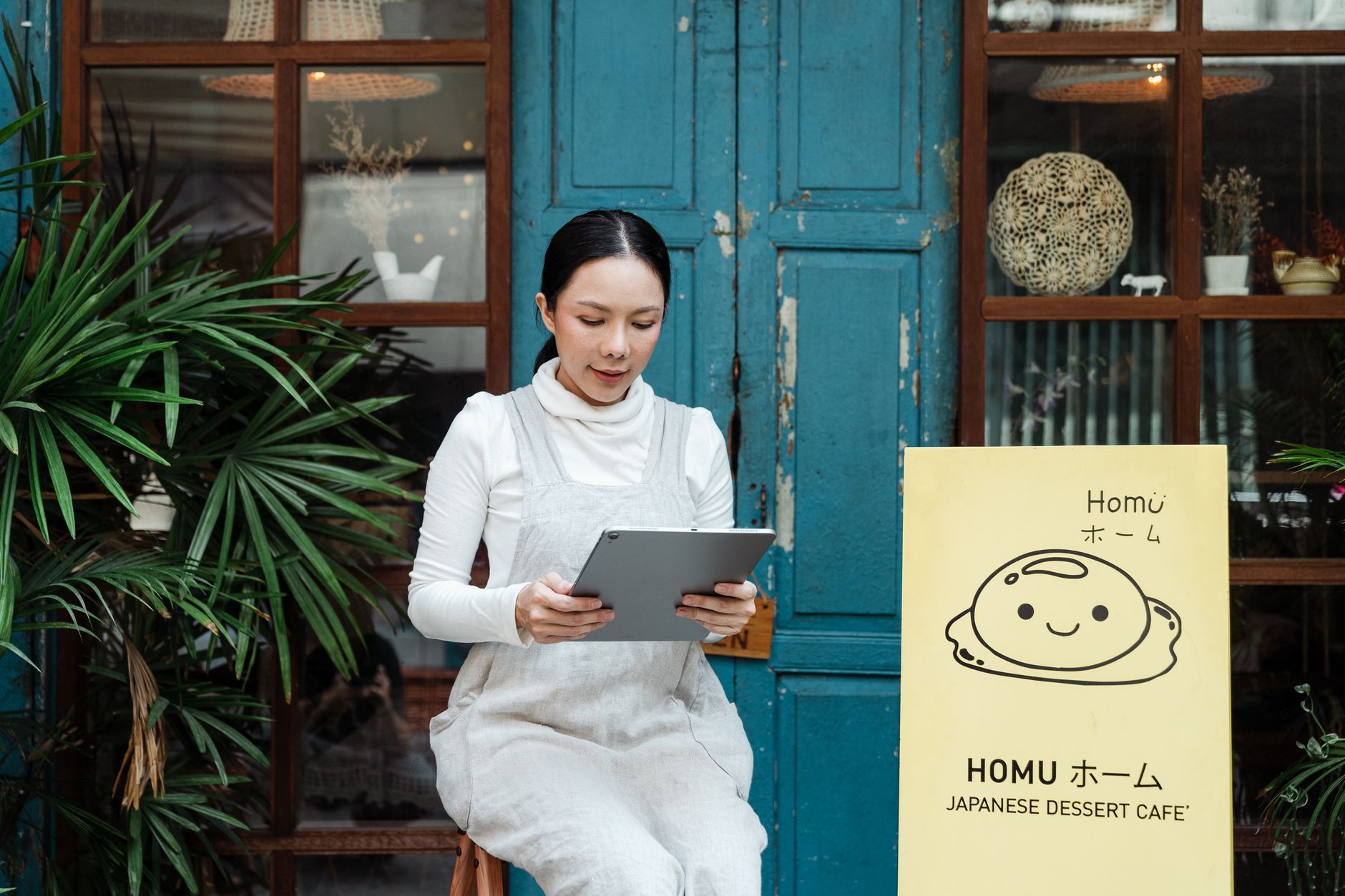 Content woman with modern tablet near cafe entrance