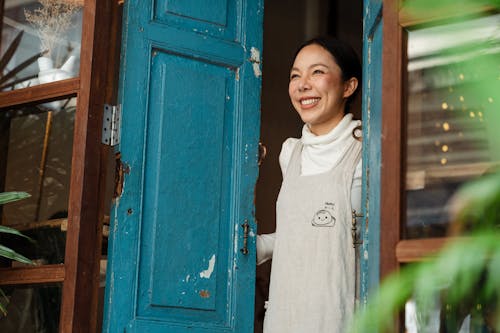 Happy ethnic coffee shop owner standing at entrance door