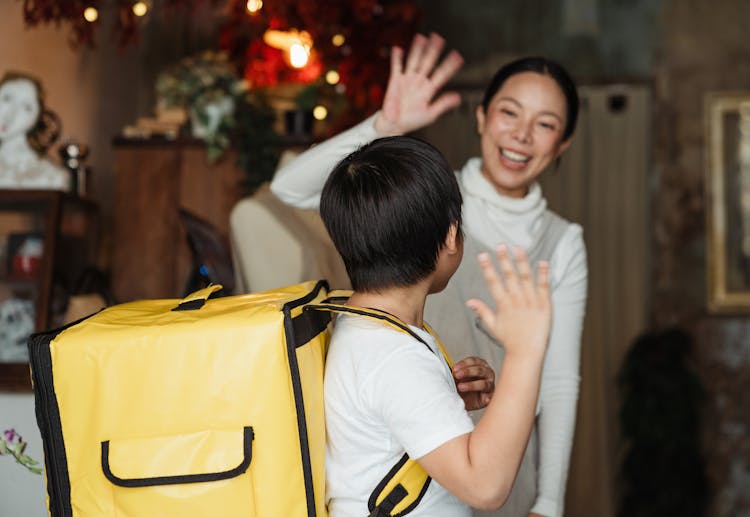 Mother Saying Goodbye To Son With Food Backpack