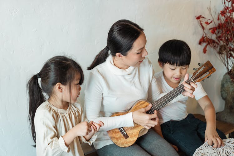 Female Musician Playing Musical Instrument For Ethnic Children At Home