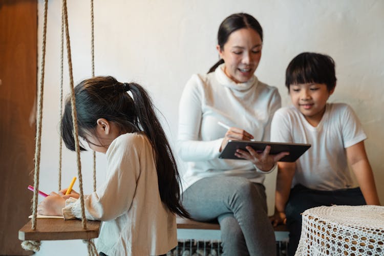 Ethnic Mother Surfing Internet On Tablet Spending Time With Children