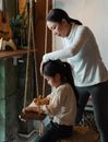 Mother palming head of daughter drawing on paper with pen
