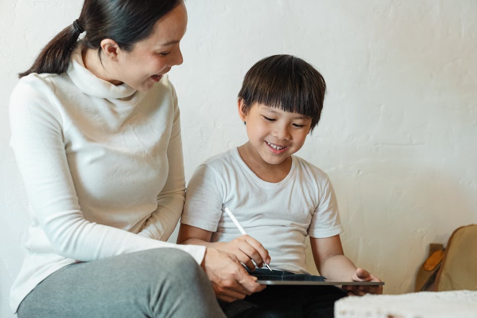 Mother and child smiling while using a tablet indoors, capturing a joyful family moment.