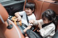 公路旅行中，少数族裔的男孩和女孩身穿休闲服装，面带微笑地坐在乘客座位上