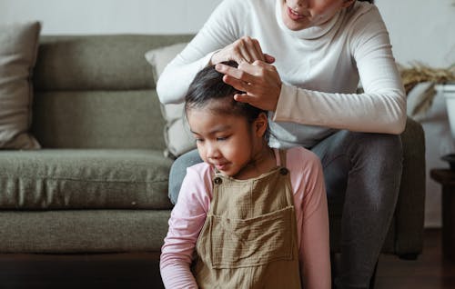 Photo of Woman Tying Her Daughter's Hair