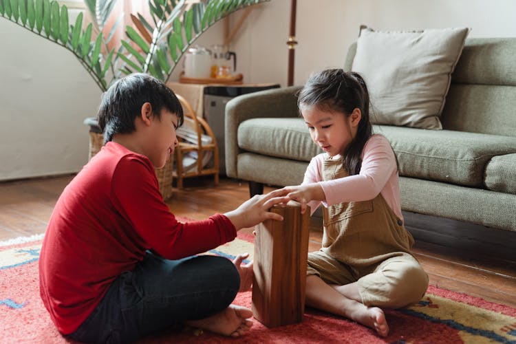 Adorable Asian Brother And Sister Playing Jenga On Floor At Home