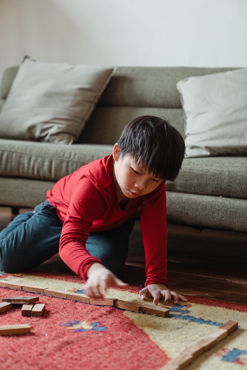 Smiling young boy playing with colorful wooden blocks in a bright playroom