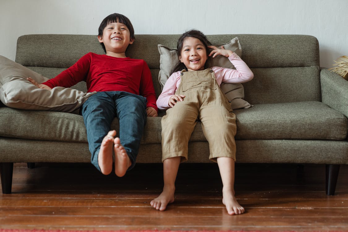 Free Photo of Two Kids Sitting on Gray Couch Stock Photo