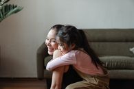 在舒适的家庭环境中，微笑的母女温暖地拥抱在一起