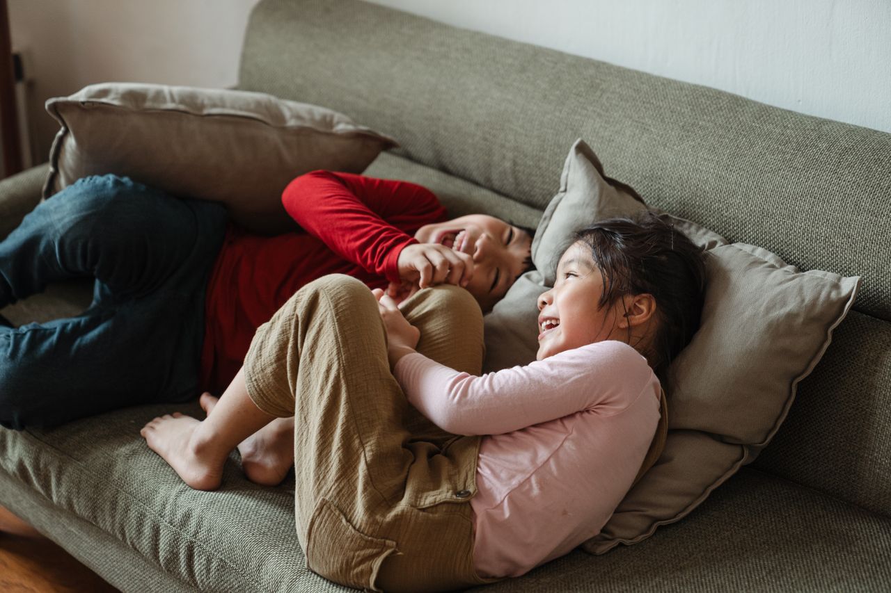 two children joyfully laughing on a sofa showcasing happiness and sibl