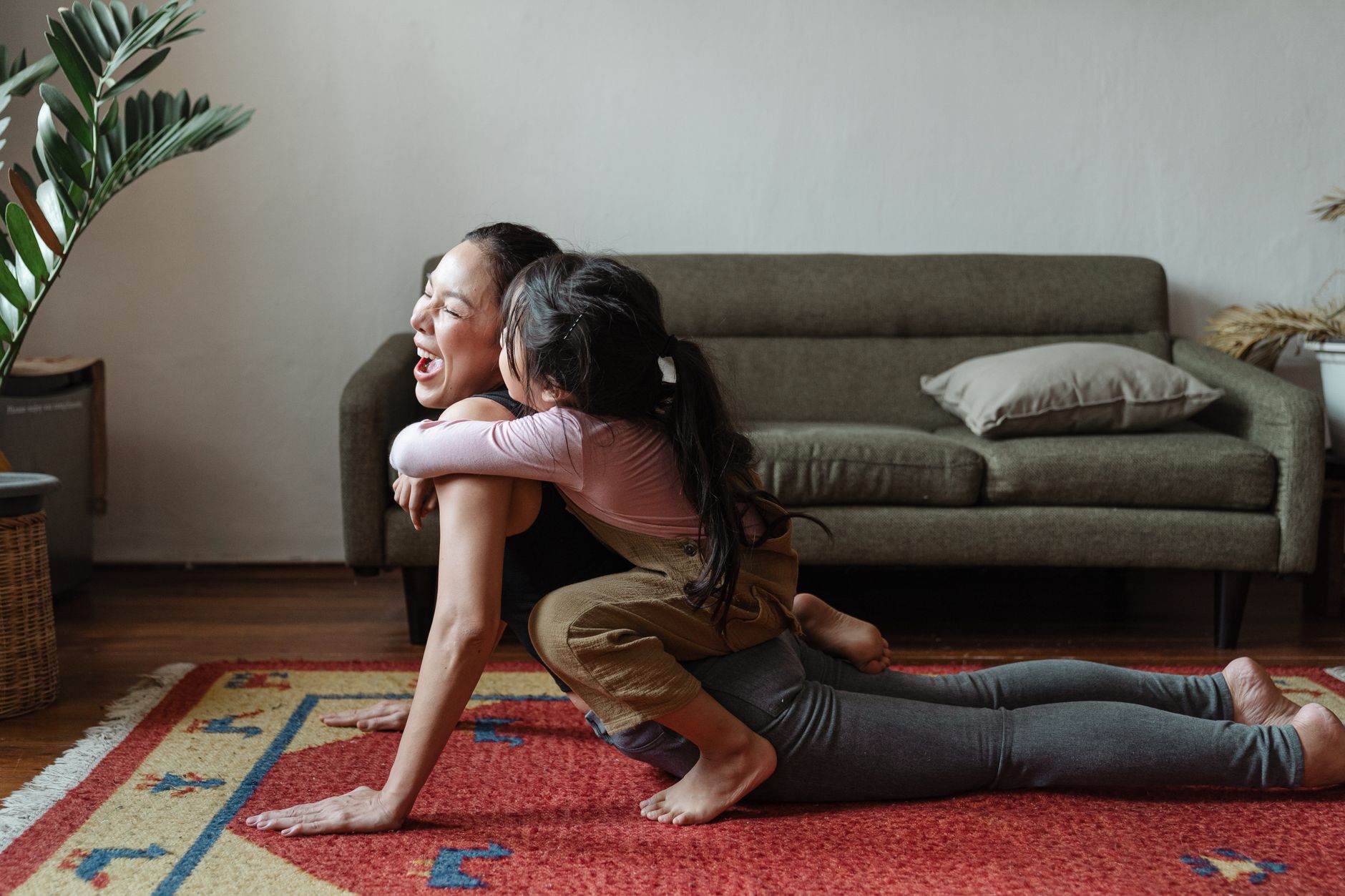 瑜伽十大好處:第七個提升免疫力的隱藏益處 A cheerful mother and daughter bonding during a vibrant yoga session in a cozy living room.