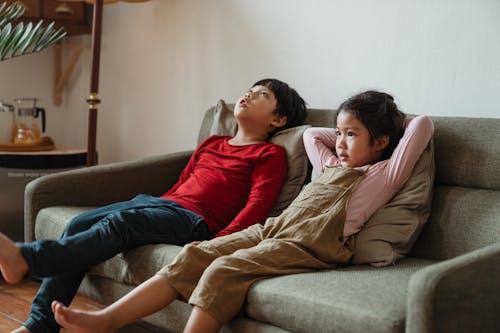 Photo of Two Kids Sitting on Gray Sofa