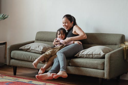Free Photo of Woman Hugging Her Child While Sitting on Gray Sofa Stock Photo