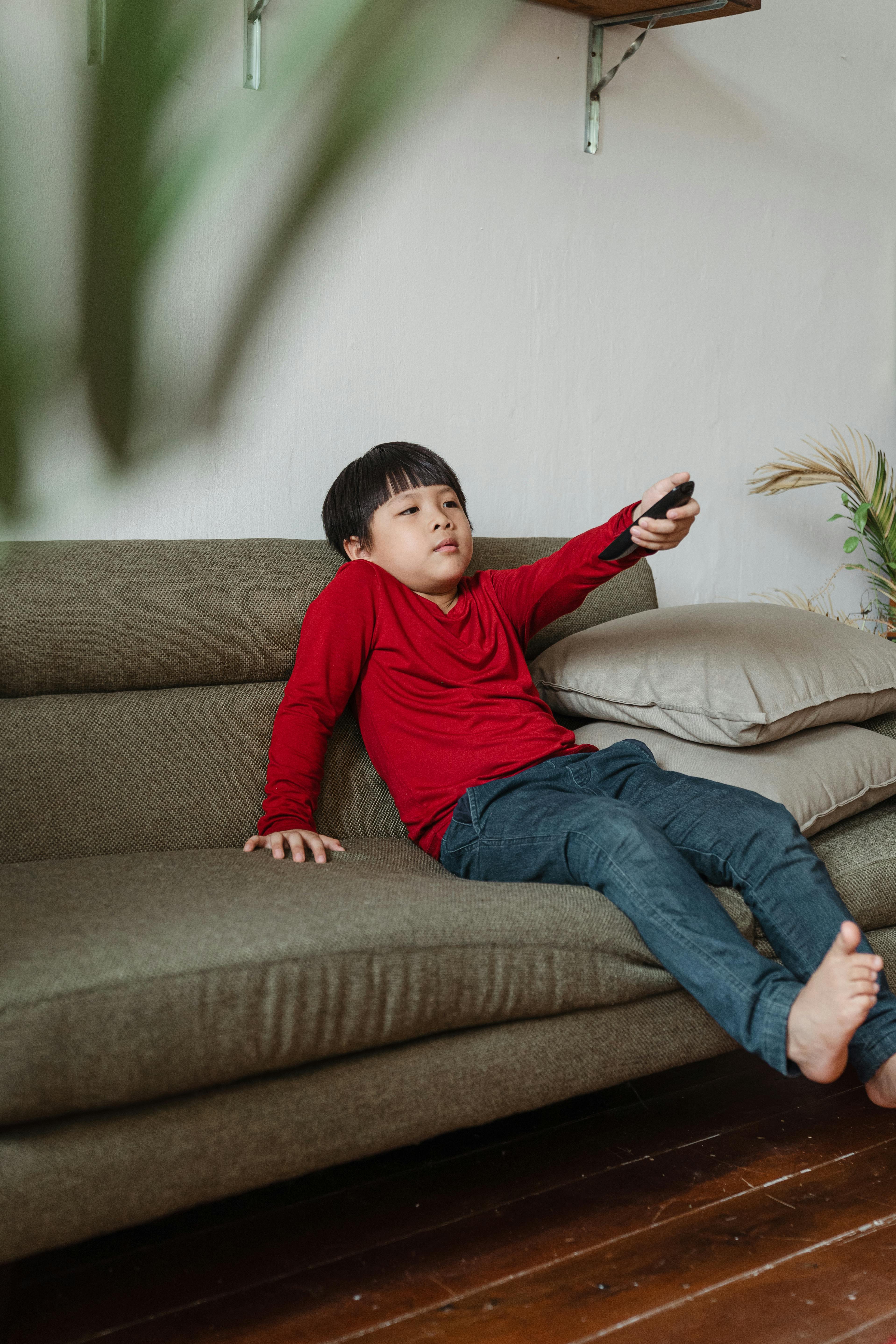 content ethnic boy resting at home watching tv