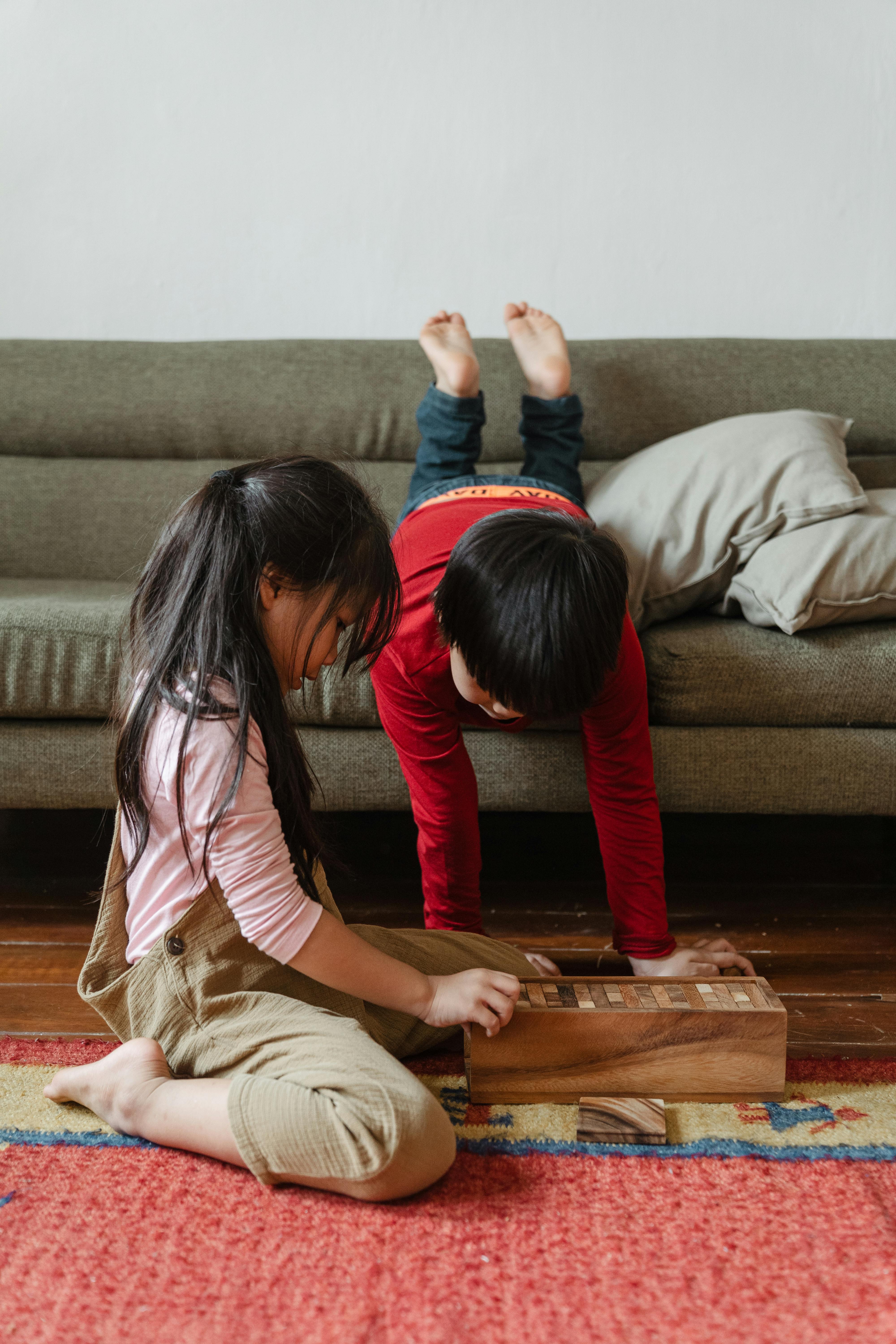 adorable barefoot ethnic brother and sister playing tower game at home