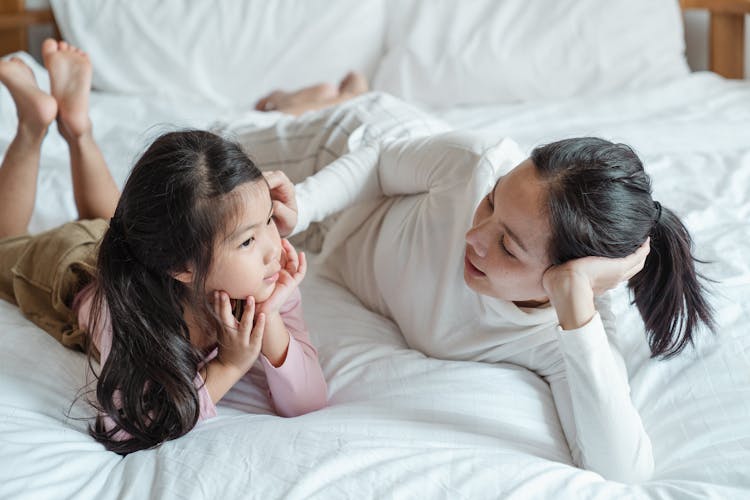 Photo Of Woman And Girl Talking While Lying On Bed