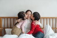 孩子们在室内拥抱床上的母亲，分享快乐的亲密时刻