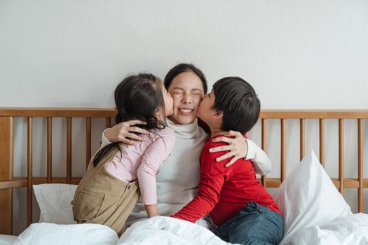孩子们在室内拥抱床上的母亲，分享快乐的亲密时刻