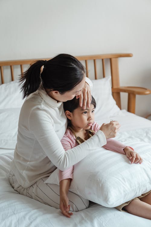 Caring mother adjusting hair of ethnic daughter