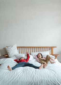 两个孩子在舒适卧室的大床上一起笑着放松