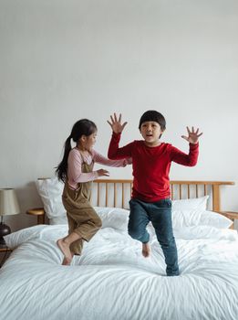 两个孩子在室内的床上快乐地蹦跳着