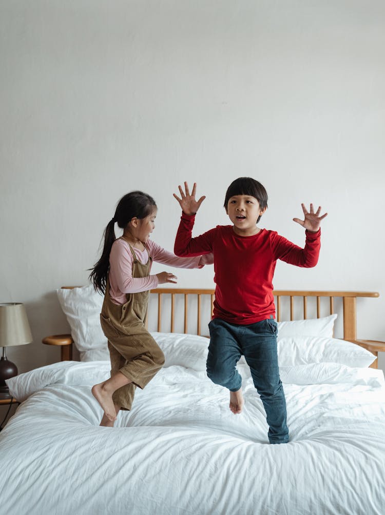 Joyful Kids Playing And Jumping On Bed