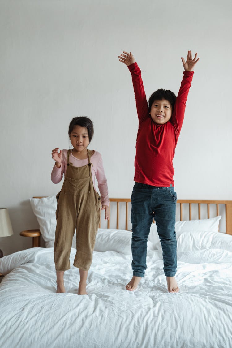 Excited Kids Jumping On Bed Together