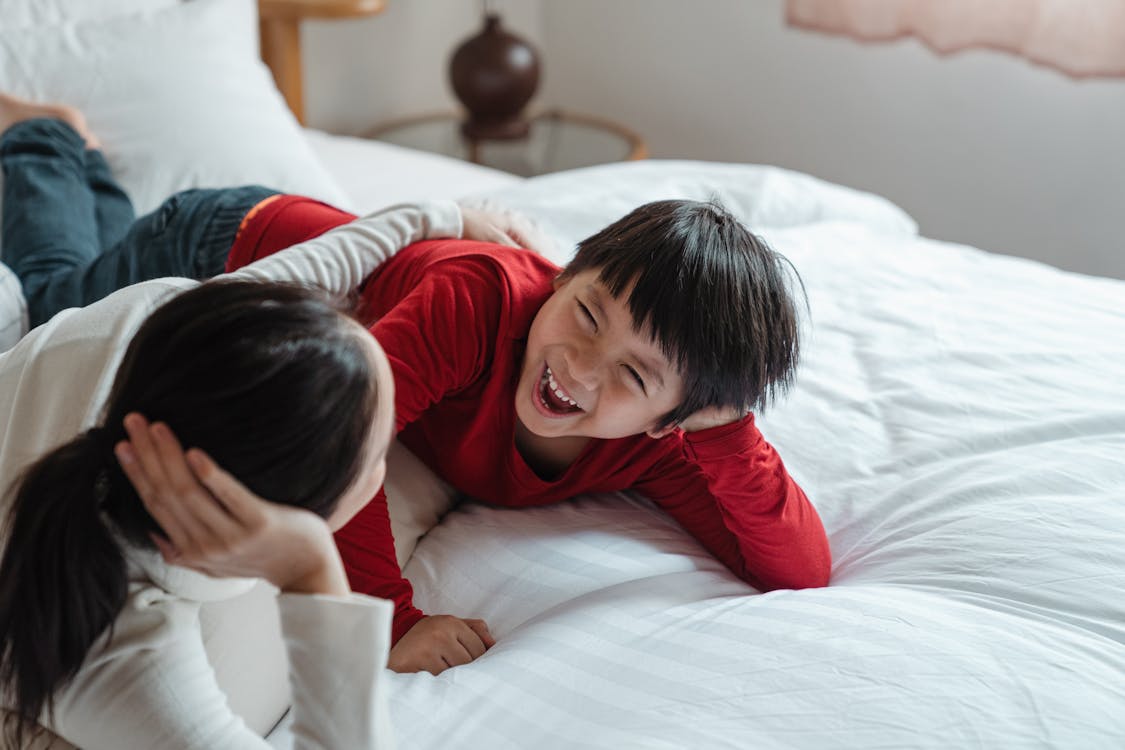 Photo of Mother and Son Lying Down on Bed